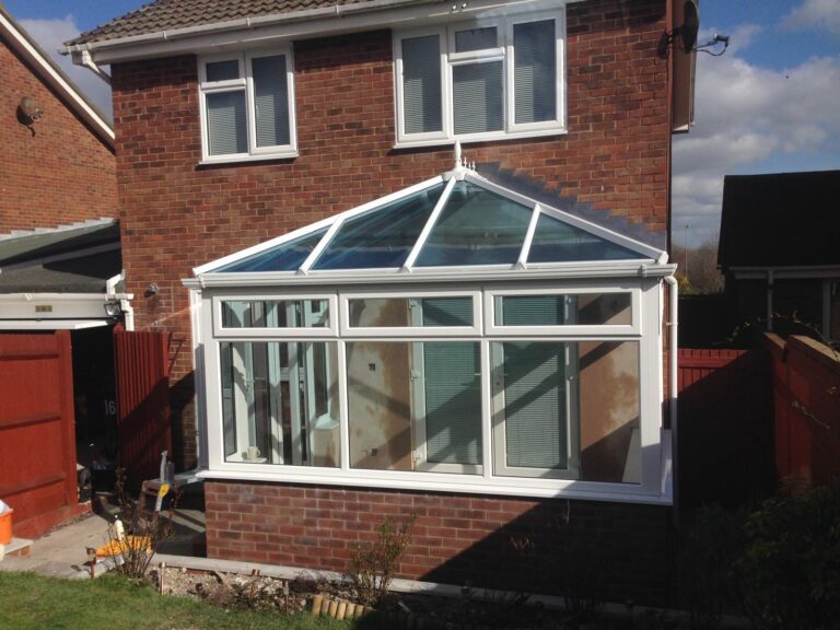 Traditional Victorian conservatory with large glass panels and a pitched roof, featuring classic ornate detailing.