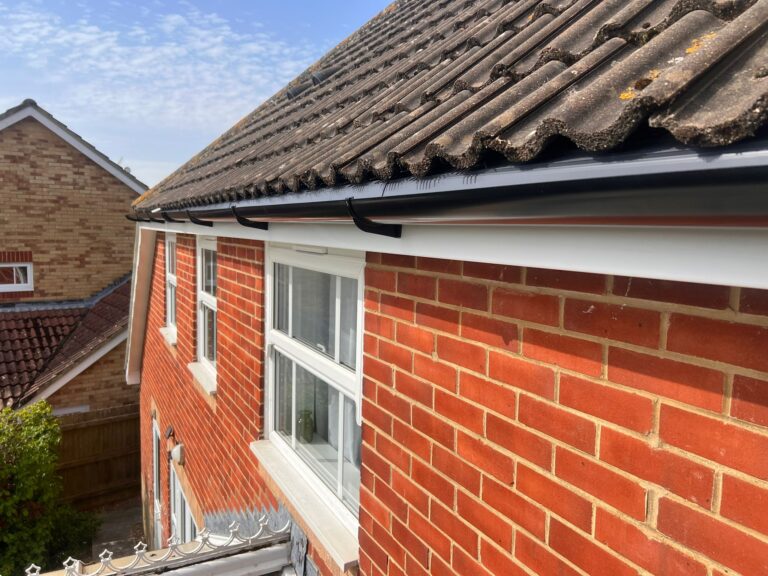 New fascia and soffit fitted along a small porch roof, with smooth white boards and black gutter brackets.