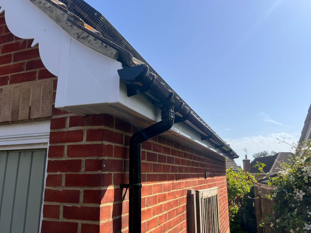 white fascia and soffit installed with black curved guttering with downpipe