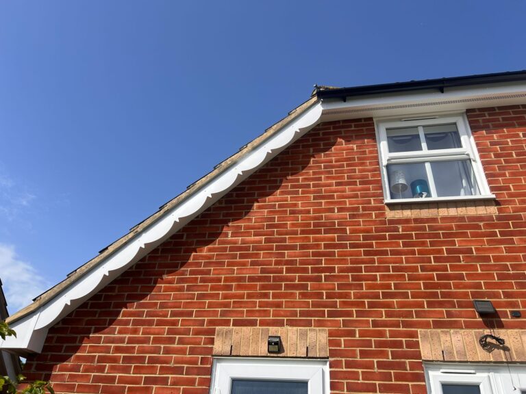 Front-facing view of a home's roof edge with new fascia and soffit panels, paired with sleek black guttering.