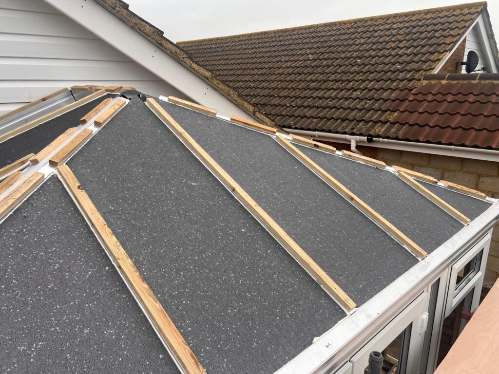 Warm roof construction showing insulation layers being installed in a conservatory showing the outside before the boards are installed on top